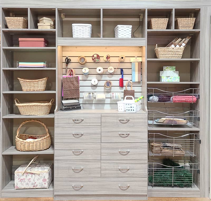 Reach in craft closet with led lighting with a baskets, shelves and drawers.