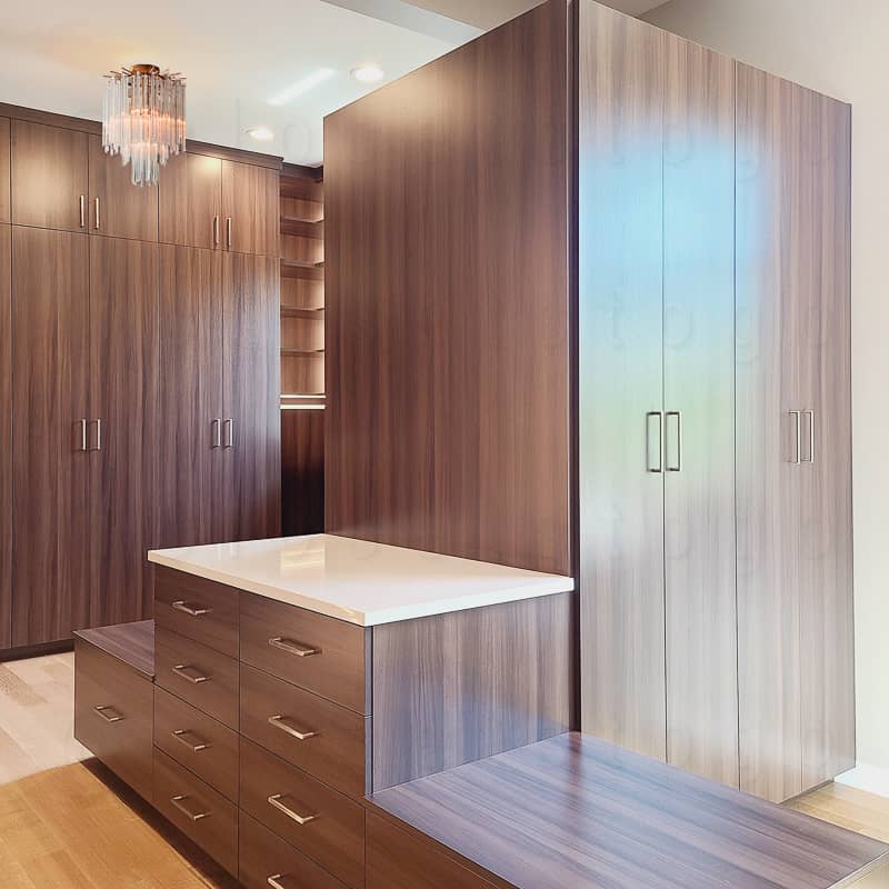 Brown walk in spacious closet with tall closed drawers and closed doors.