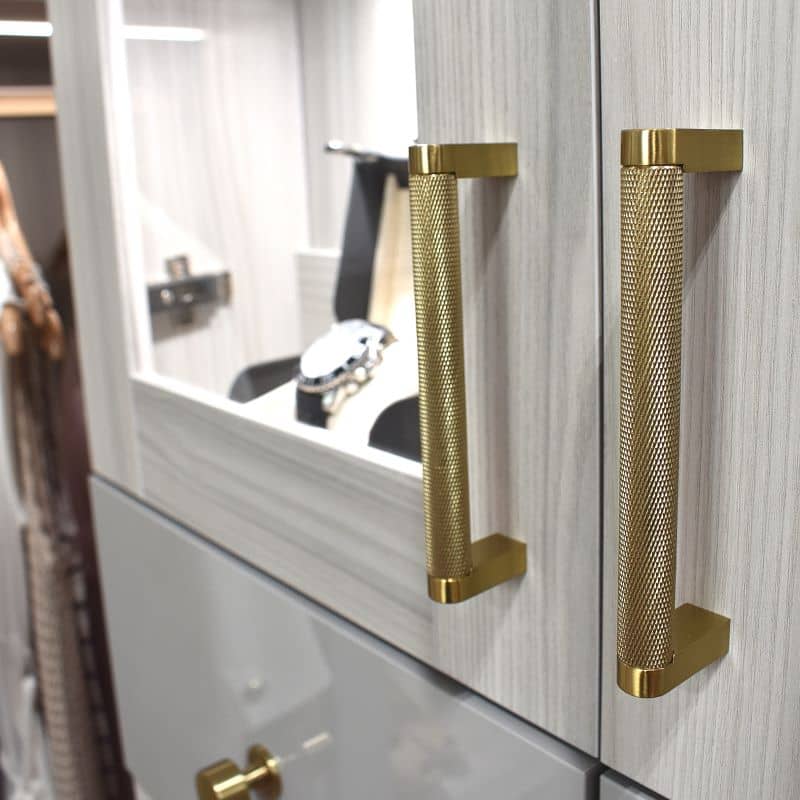 A Luxury White Closet with a island in the center, several drawers and long doors for long hang.