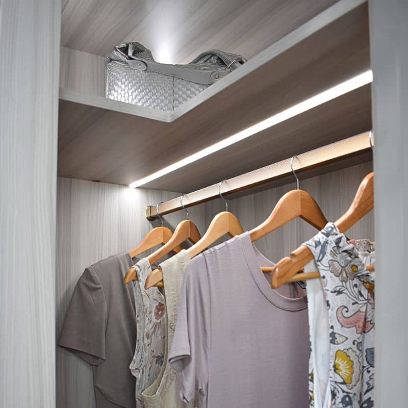 A Luxury White Closet with LED lighting, with medium hanging drawers, drawers, shelves.