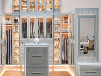 Walk in two toned grey and white closet with some glass doors and led lights