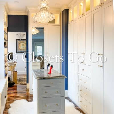 White walk in cloest with closet doors and island.