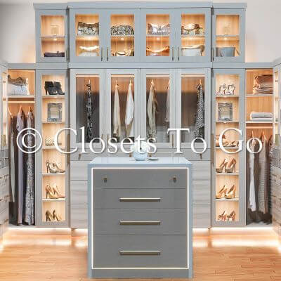 Grey LED luxury walk in closet with glass doors to display shoes.