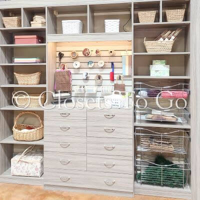 Reach in craft closet with drawers, shelves and baskets.