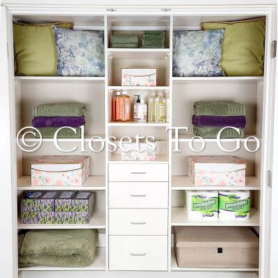 Reach in white linen closet with drawers and shelves.