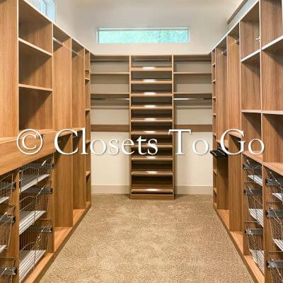 Walk in brown closet with several shelves and baskets.